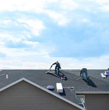 4 construction workers fixing roof against clouds blue sky, install shingles at the top of the house. Renovate, improvement, build home exterior by professional teamwork. Safety and protection concept